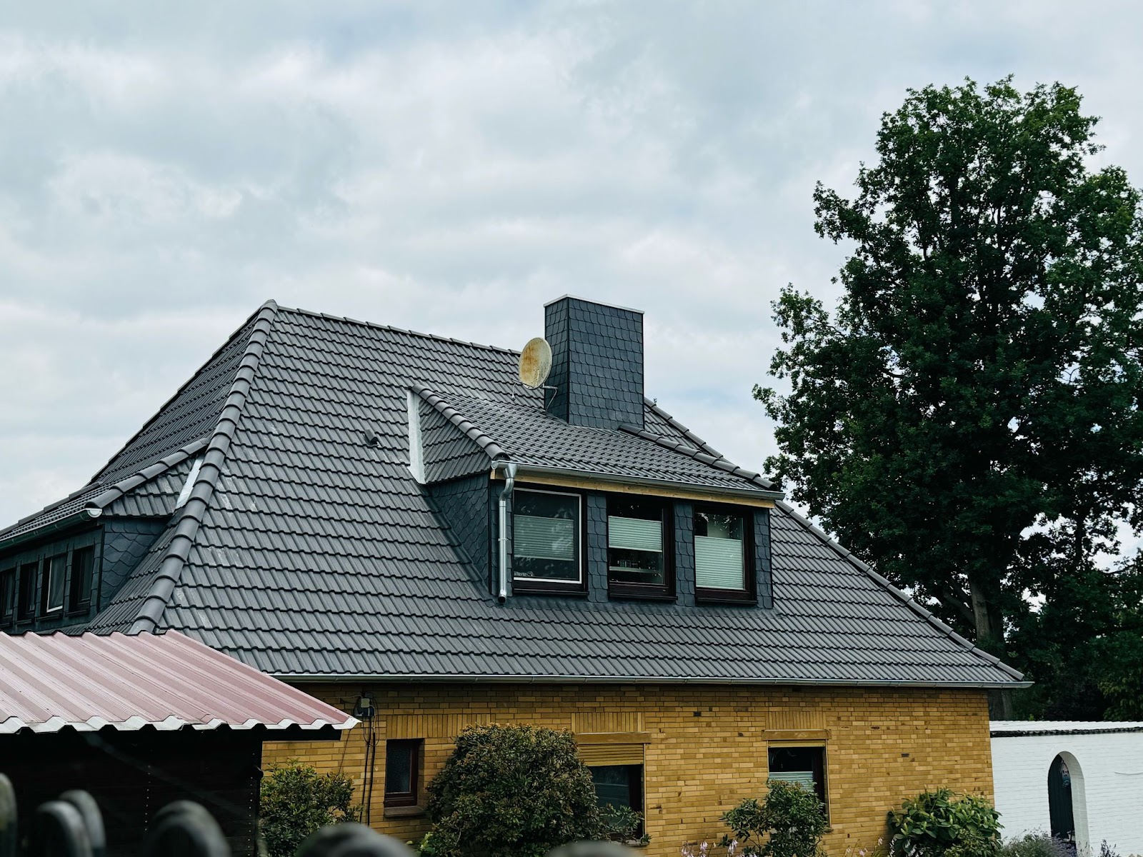 Neu eingedecktes Walmdach mit Gaube und Schornstein aus Schiefer